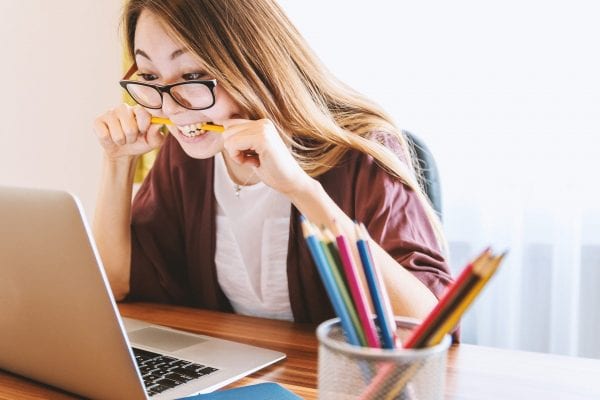 A teacher new to distance learning bites her pencil in frustration