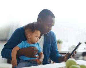 a student looks at his mobile learning platform while holding his child