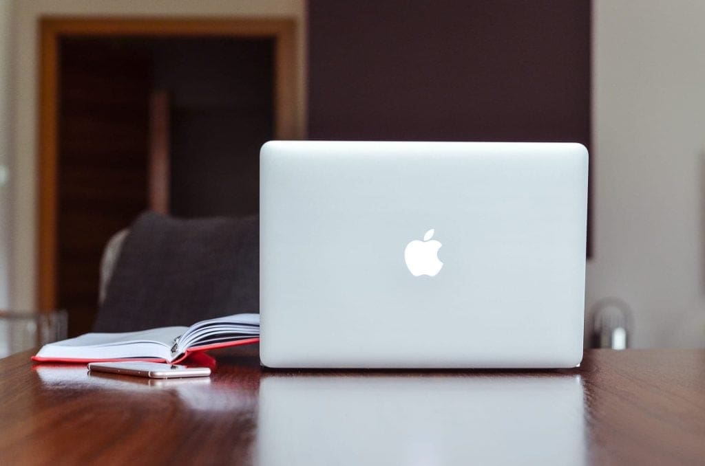 a notebook lies open next to a laptop