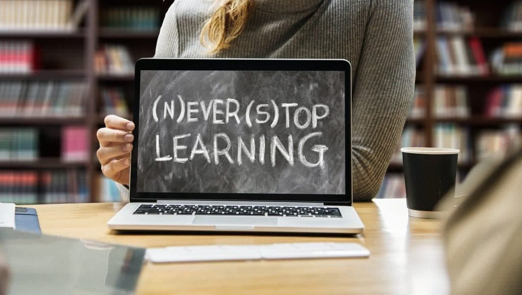 a student in a library with a laptop that reads never stop learning